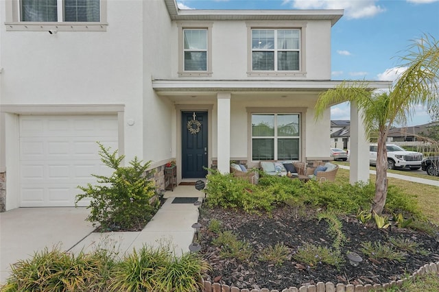 view of front of home featuring stucco siding, an attached garage, covered porch, concrete driveway, and stone siding