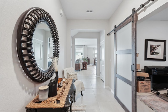 hallway featuring a barn door, light tile patterned floors, and baseboards