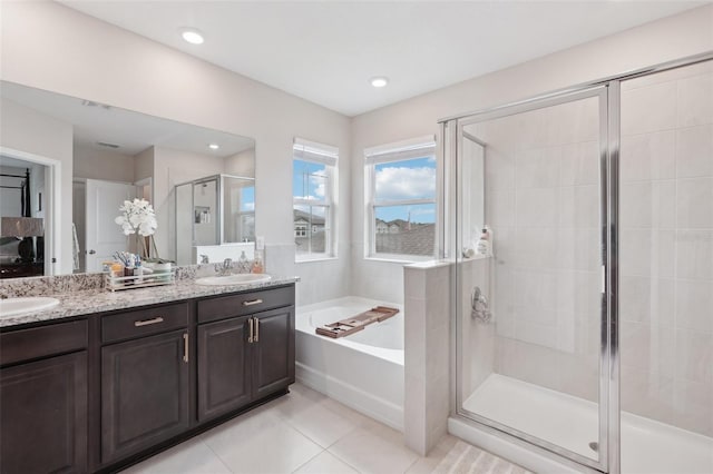bathroom featuring a bath, a shower stall, tile patterned flooring, double vanity, and recessed lighting