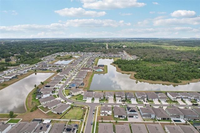 view of property location with nearby suburban area, a nearby body of water, and a forest