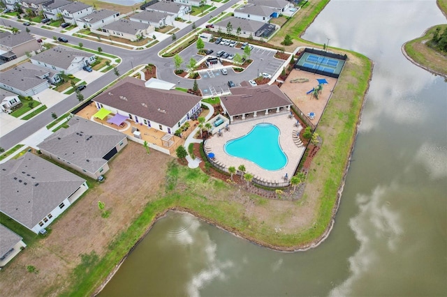 aerial perspective of suburban area featuring a pool area and a large body of water