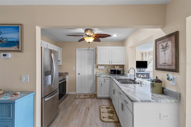 9743 36th Way N Unit 4, Pinellas Park, FL 33782 - kitchen featuring stainless steel appliances, a sink, white cabinetry, light wood finished floors, and light stone countertops