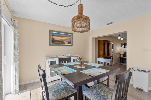 9743 36th Way N Unit 4, Pinellas Park, FL 33782 - dining room featuring a chandelier, light wood finished floors, baseboards, and a textured ceiling