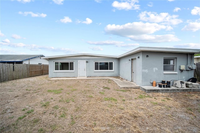rear view of house with stucco siding and fence private yard