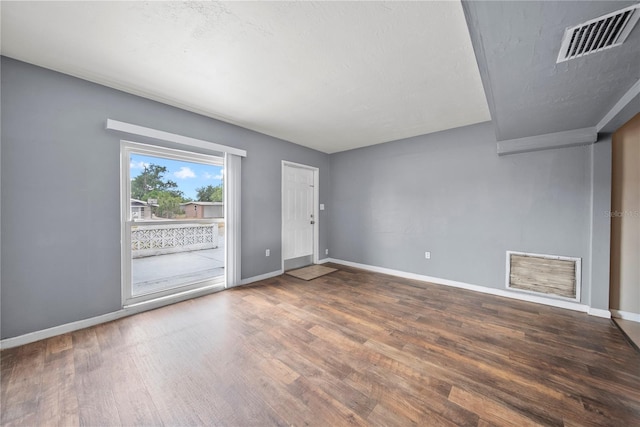 unfurnished room featuring baseboards, visible vents, and wood finished floors