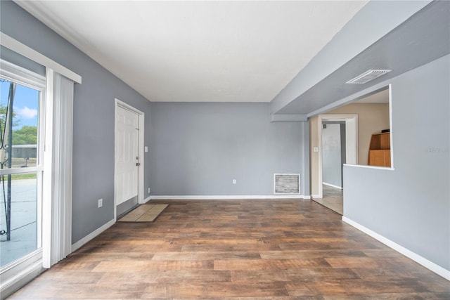 spare room with baseboards, visible vents, and wood finished floors