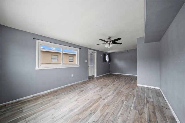 empty room with baseboards, wood finished floors, and a ceiling fan