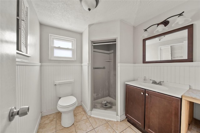 full bath with a wainscoted wall, toilet, a stall shower, and a textured ceiling