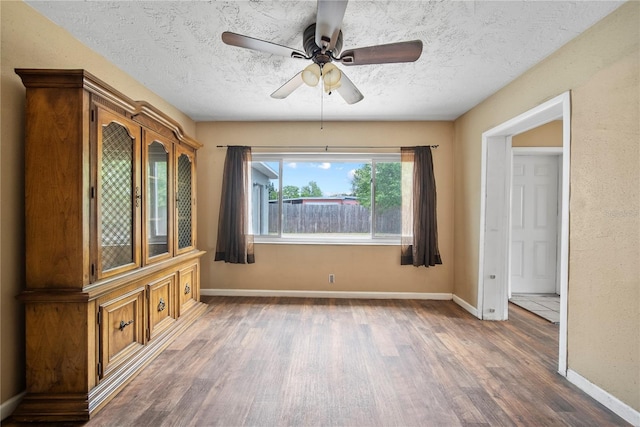 spare room featuring ceiling fan, a textured ceiling, baseboards, and wood finished floors