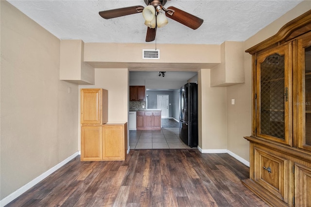 unfurnished room featuring baseboards, visible vents, a textured ceiling, and dark wood-type flooring