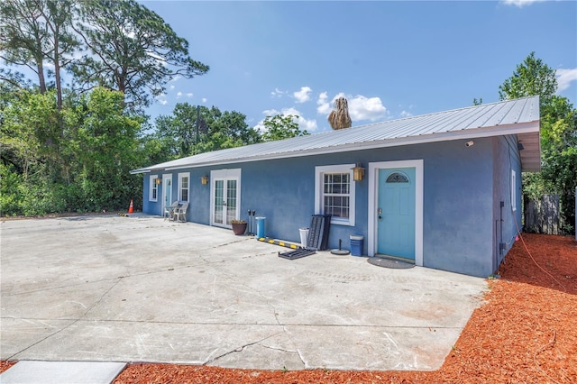 6515 Dimarco Rd, Tampa, FL 33634 - view of front of property featuring stucco siding, metal roof, a patio, and french doors