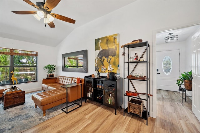 living area featuring vaulted ceiling, a ceiling fan, and wood finished floors