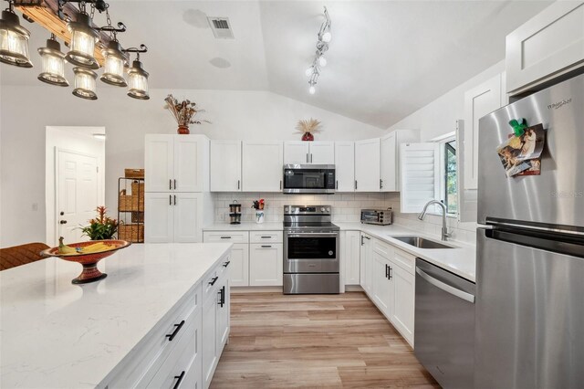kitchen with a sink, stainless steel appliances, white cabinetry, visible vents, and vaulted ceiling