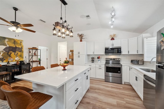 kitchen with lofted ceiling, visible vents, a breakfast bar area, and appliances with stainless steel finishes