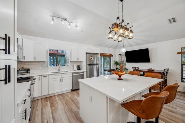 kitchen featuring a sink, stainless steel appliances, visible vents, light wood-style flooring, and a kitchen island