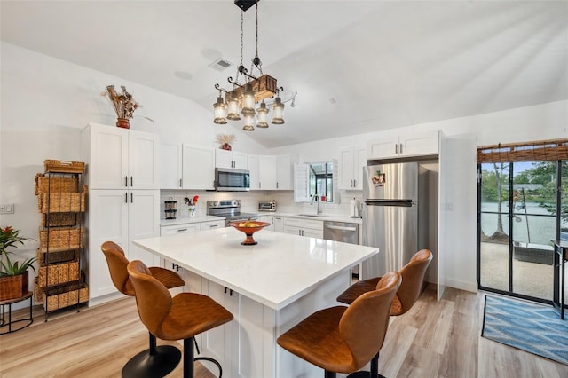 kitchen with visible vents, a kitchen breakfast bar, appliances with stainless steel finishes, and a sink