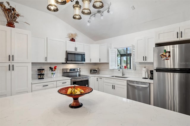 kitchen featuring a sink, white cabinetry, appliances with stainless steel finishes, decorative backsplash, and lofted ceiling