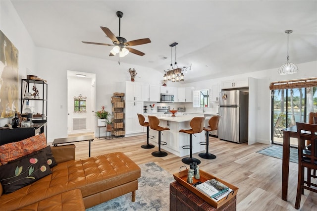 living room with light wood-type flooring, lofted ceiling, a ceiling fan, and a healthy amount of sunlight