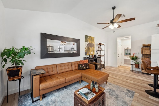 living area with light wood finished floors, visible vents, baseboards, ceiling fan, and vaulted ceiling
