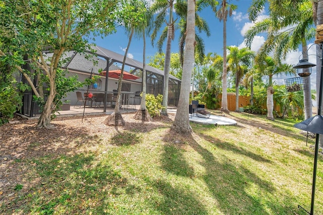 view of yard featuring fence, a patio, and a lanai