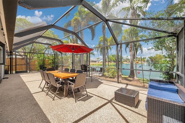 view of patio featuring a water view, outdoor dining space, and glass enclosure