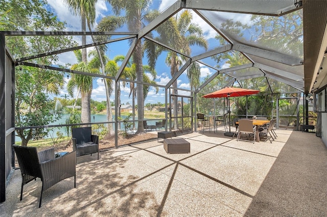 view of patio featuring a water view, glass enclosure, and outdoor dining area