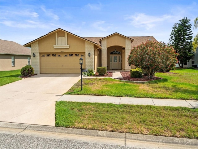 view of front facade with a garage, concrete driveway, a front yard, and stucco siding