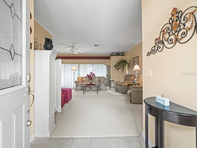 living area with light carpet, ornamental molding, ceiling fan, light tile patterned flooring, and baseboards