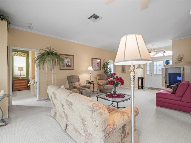 living area featuring light colored carpet, ornamental molding, baseboards, and a ceiling fan