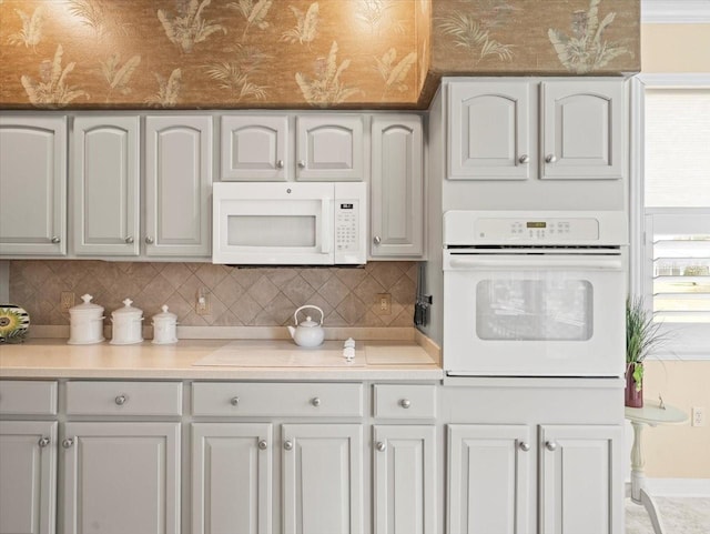 kitchen featuring white appliances, decorative backsplash, and light countertops