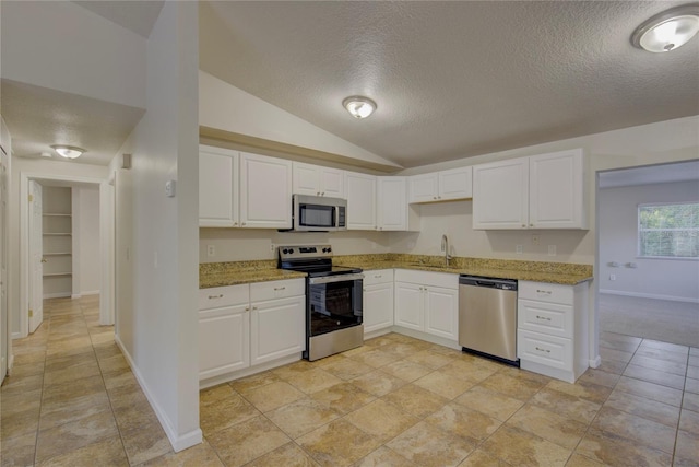 10319 Widgeon Way, New Port Richey, FL 34654 - kitchen featuring stainless steel appliances, a sink, a textured ceiling, baseboards, and light stone countertops