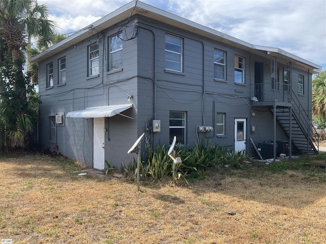 rear view of house with stairs and a lawn