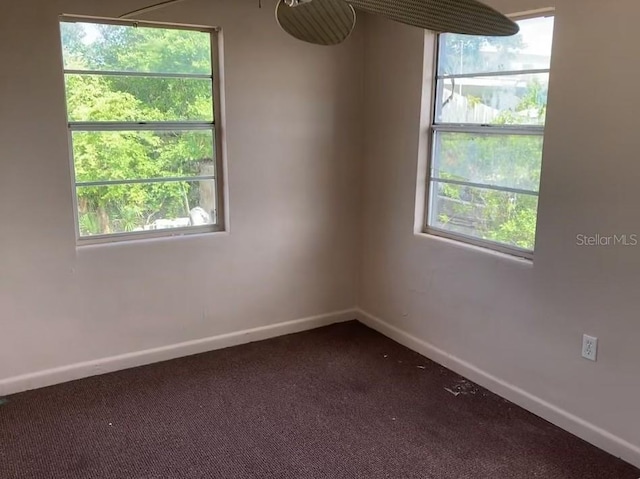 spare room with baseboards, dark carpet, and healthy amount of natural light