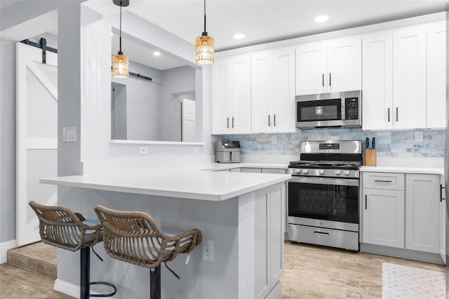 5421 Gay St, Weeki Wachee, FL 34607 - kitchen with recessed lighting, a barn door, a kitchen breakfast bar, light countertops, and appliances with stainless steel finishes