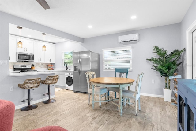 5421 Gay St, Weeki Wachee, FL 34607 - kitchen with washer / clothes dryer, a wall mounted air conditioner, a breakfast bar area, a sink, and stainless steel appliances