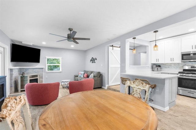 5421 Gay St, Weeki Wachee, FL 34607 - dining space featuring a brick fireplace, light wood-type flooring, a barn door, ceiling fan, and recessed lighting