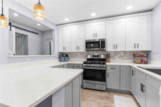 5421 Gay St, Weeki Wachee, FL 34607 - kitchen with stainless steel appliances, tasteful backsplash, decorative light fixtures, a barn door, and recessed lighting