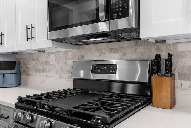 5421 Gay St, Weeki Wachee, FL 34607 - kitchen featuring white cabinets, light countertops, decorative backsplash, and stainless steel appliances
