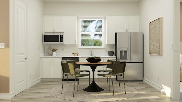 6905 E 116th Ct, Palmetto, FL 34221 - kitchen featuring white cabinetry, light countertops, light wood-type flooring, and appliances with stainless steel finishes