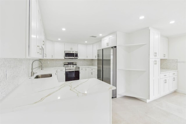 kitchen with appliances with stainless steel finishes, a sink, open shelves, light stone counters, and tasteful backsplash