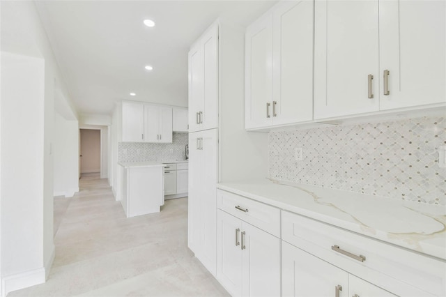 kitchen featuring light stone countertops, white cabinets, backsplash, recessed lighting, and a sink