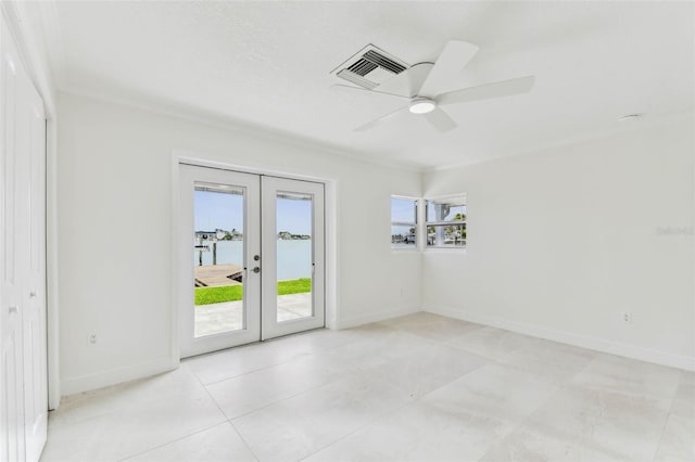 spare room with french doors, a ceiling fan, baseboards, crown molding, and a water view