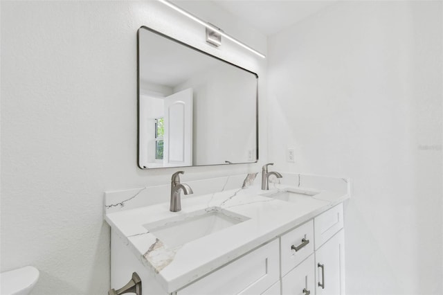 bathroom with double vanity and toilet