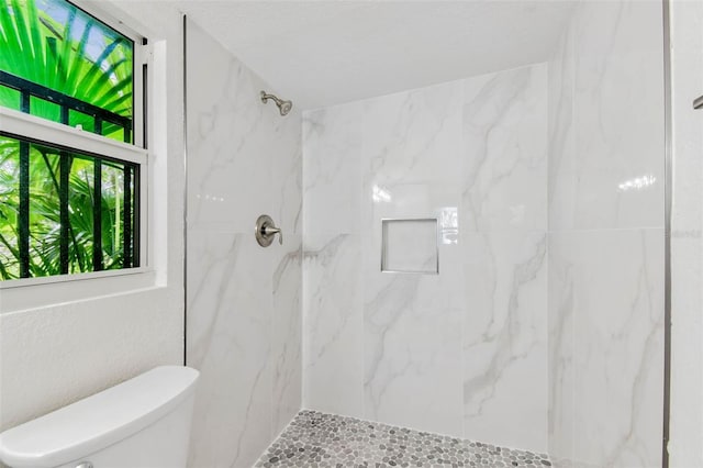 full bathroom with a marble finish shower and toilet