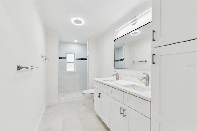 bathroom featuring baseboards, tiled shower, toilet, and double vanity