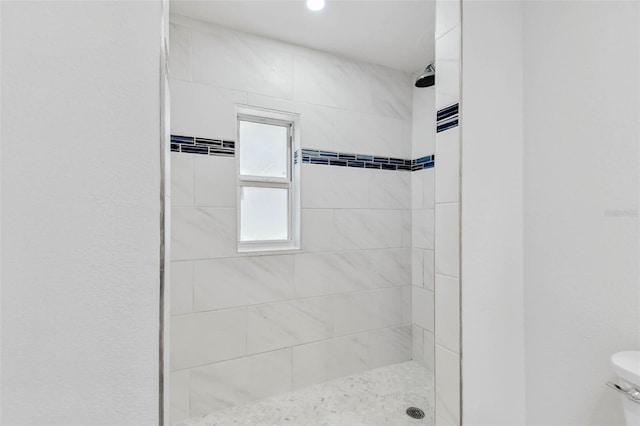 bathroom featuring tiled shower and toilet