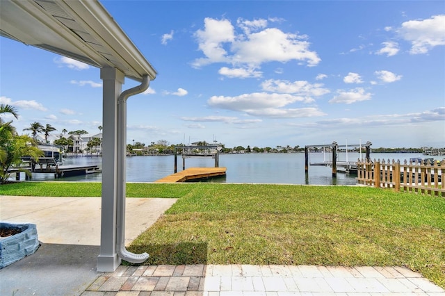 dock area with a water view, a lawn, and boat lift