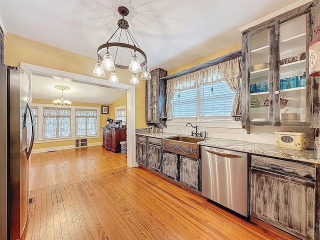 800 W Lake Elbert Dr NE, Winter Haven, FL 33881 - kitchen featuring appliances with stainless steel finishes, a chandelier, light wood-type flooring, glass insert cabinets, and decorative light fixtures