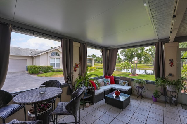 sunroom featuring a water view, rail lighting, and an outdoor living space