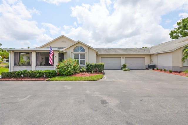 ranch-style home featuring stucco siding, a garage, concrete driveway, and central AC